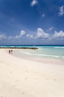 WEST INDIES, Barbados, Christ Church, Couple walking towards sea defences on Rockley Beach also