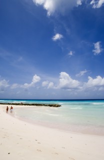 WEST INDIES, Barbados, Christ Church, Couple walking towards sea defences on Rockley Beach also