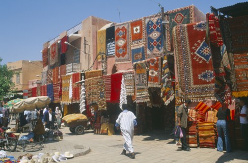 MOROCCO, Marrakesh, The souk with carpets displayed from walls and awnings of shopfronts opposite