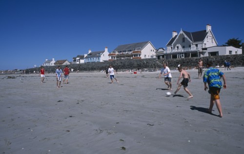 UNITED KINGDOM, Channel Islands, Guernsey, Castel. Cobo Bay. Young men playing football on sandy