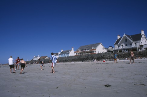 UNITED KINGDOM, Channel Islands, Guernsey, Castel. Cobo Bay. Young men playing football on sandy