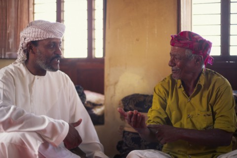 OMAN, Sur, "Discussioin between two Omanis, including traditional fisherman on the right hand side