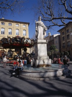 FRANCE, Aix en Provence, "Statue in centre of water fountain, people sat on edge. Carousel and