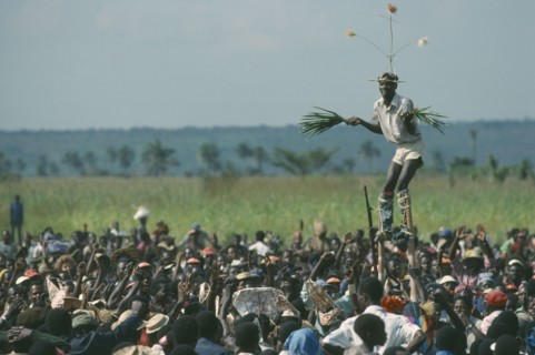 CONGO, Gungu, Stilt walker above crowds at Bapende tribe Gungu Festival.