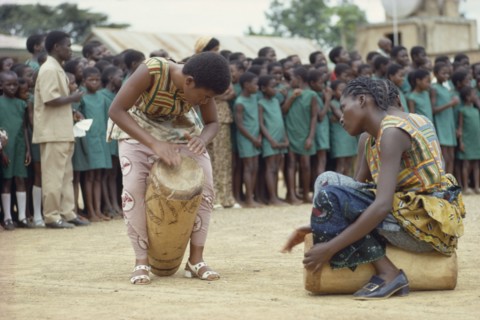 CONGO, Tribal People, African women drummers with group of schoolchildren listening behind.