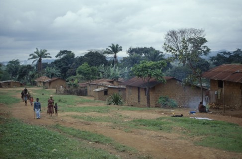 ANGOLA, Vige, Mud brick village houses with people on unmade road outside.