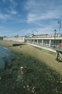 ENGLAND, Hampshire, Portsmouth, Old Portsmouth. Family playing amongst rocks on stretch of shingle