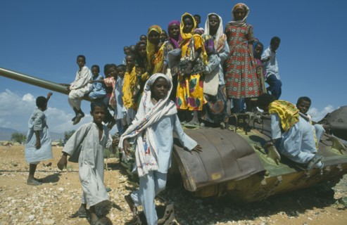 ERITREA, Children, Children playing on rusting tank on road between Asmara and Keren near Aderde.