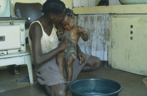 SOUTH AFRICA, Children, Bathing, Mother bathing baby daughter inside home.