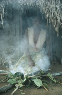 SUDAN, South, Rituals, Azande tribeswoman kneeling over fire to purify herself after giving birth.