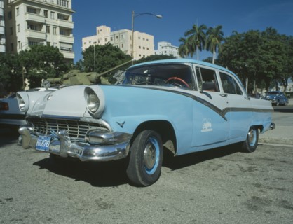 CUBA, Havana, A blue and white taxi parked ouside the Museo de la Revolution with a tank behind.