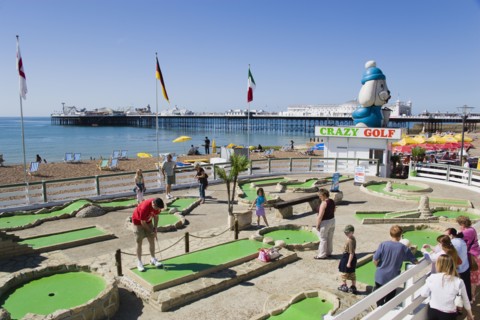 ENGLAND, East Sussex, Brighton, Tourist family playing crazy golf on the seafront with Brighton