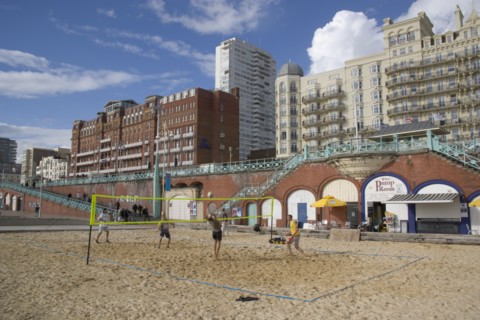 ENGLAND, East Sussex, Brighton, Young men playing Volleyball on the lower esplanade. Seafront Hotel
