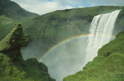 ICELAND, Skogarfoss, Rainbow over plunging waterfall from the south coast road.