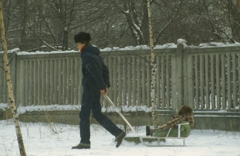 Russia, Moscow, "Father pulling child on sledge through the snow, both wrapped up against the cold