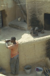 BURKINA  FASO, Sapone, Young man standing against wall in traditional Gurunsi village.