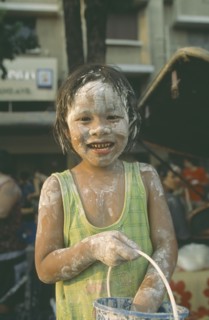 THAILAND, Bangkok, "Young girl with bucket, covered in mud at the Songkhran Festival. Thai New