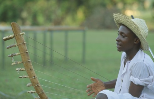 UGANDA, Kampala, Folk musician playing harp like instrument.