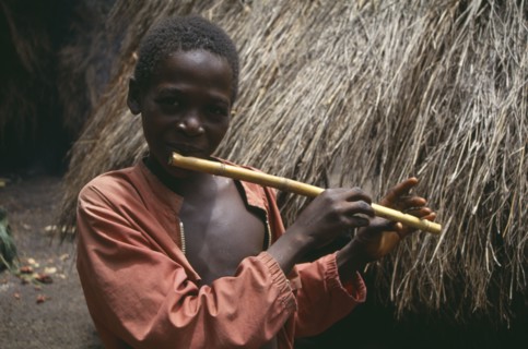 SIERRA LEONE, Kambia, Young boy playing home made flute.