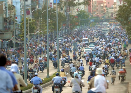 VIETNAM, South, Ho Chi Minh City, View down busy street with people riding motorbikes and bicycles