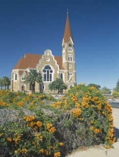 NAMIBIA, Windhoek, Christuskirche church exterior viewed from Parliament Gardens with a flowering