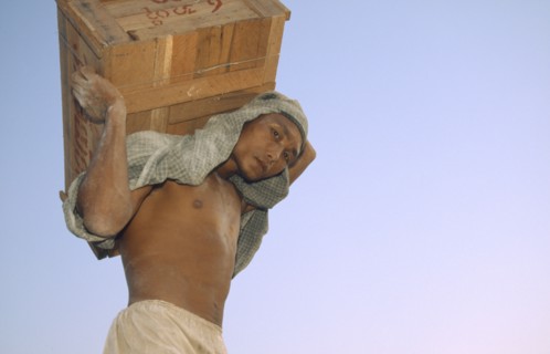 MYANMAR, Mandalay Dock, "Man carrying a crate above his head, wearing head scarf. Banks of the