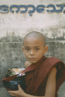 MYANMAR, Kawthoung, Young novice monk with bowl full of Alms offerings.