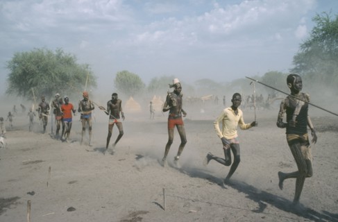 SUDAN, People, Young Dinka men carrying spears and running in line.
