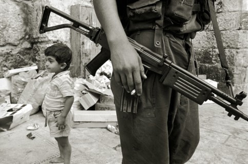 ISRAEL, Jerusalem, "Israeli soldier with rifle and cigarette relaxes in the Arab Quarter, small boy