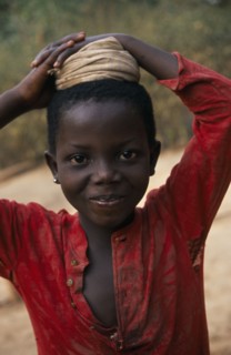 GHANA, Children, Portrait of young girl with coiled cloth on her head for carrying water pot.