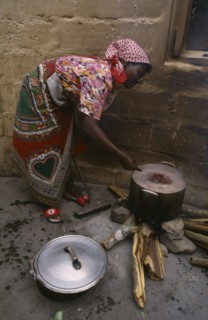 MOZAMBIQUE, People, Cooking, Woman refugee cooking beans in pot over open fire.