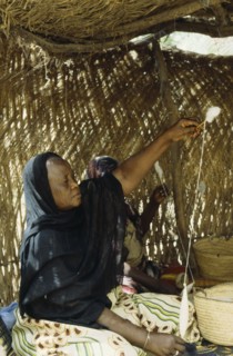CHAD, N Djamena, Woman spinning cotton inside straw hut