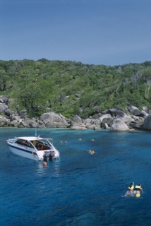 THAILAND, Similan Islands, Ko Bangu, Snorkelers in the water next to a small motor boat near the