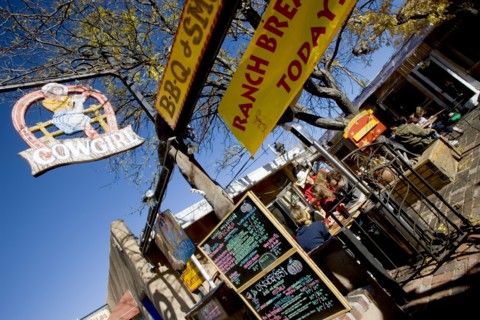 USA, New Mexico, Santa Fe, The Cowgirl Cafe outdoor eating area with customers and a waiter. Sign