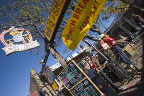 USA, New Mexico, Santa Fe, The Cowgirl Cafe outdoor eating area with customers and a waiter. Sign
