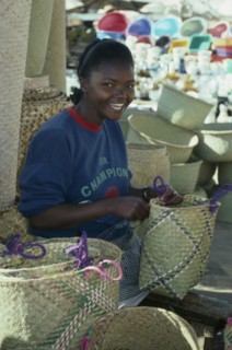 MADAGASCAR, Antananarivo, Girl making rafia baskets on market stall.