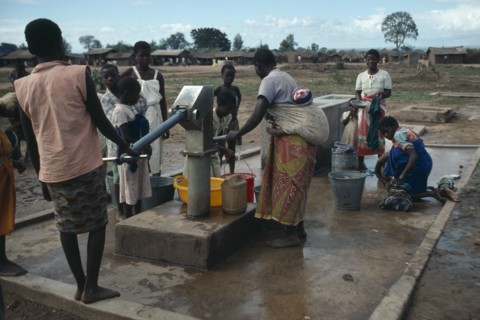 MALAWI, Refugees, Mozambican women and children at water pump in refugee camp.