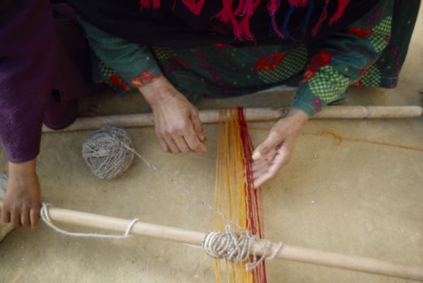 EGYPT, Western Desert, Bedouin, Cropped view of Bedouin woman and child weaving coloured yarn.