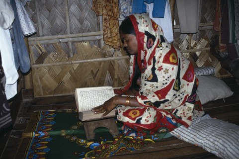 BANGLADESH, Religion, Islamic, Woman reading the koran in home in slum area.