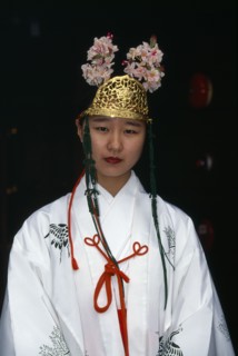 JAPAN, Honshu, Osaka, Portrait of a miko or shrine maiden at small Shinto temple in Osaka.