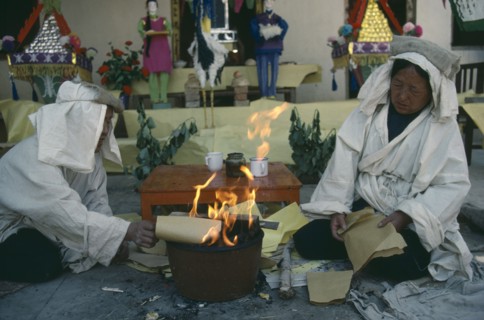 CHINA, Gansu Province, Symbolic paper money burnt at Taoist funeral with close relatives wearing