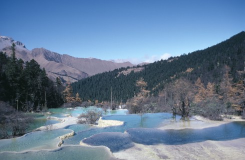 CHINA, Sichuan Province, Huanglong, View across pools formed by calcium carbonate in water towards