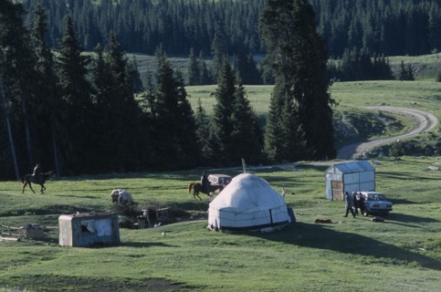 KIRGHIZSTAN, Tyan Shan, "Two men on horses, some standing around a car next to a yurt and small