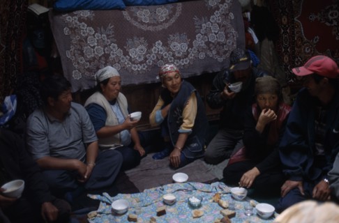 KIRGHIZSTAN, Workers, "Shepherds inside a yurt, eating and drinking, large rugs hanging on the