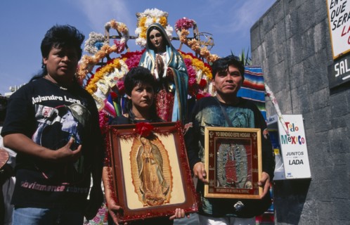 MEXICO, Mexico City, Pilgrims carrying icons and standing in front of statue of the Virgin Mary