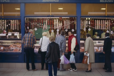 HUNGARY, Budapest, Tourists buying salami from butchers with counter open on to street.