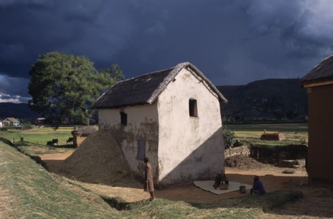 MADAGASCAR, Architecture, Road to Ambositra. Women outside thatched white building with straw in a