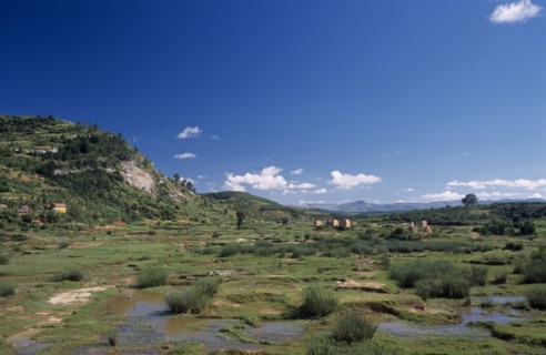 MADAGASCAR, Landscape, Road to Ambalavao. View across green flood plain  towards clay brick kilns