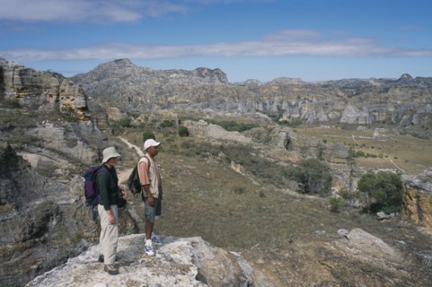 MADAGASCAR, Isalo National Park, Tourist and guide standing on edge of rock looking over craggy
