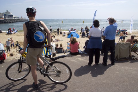 ENGLAND, Dorset, Bournemouth, Tourists playing in the sand and watching speedboat races off the